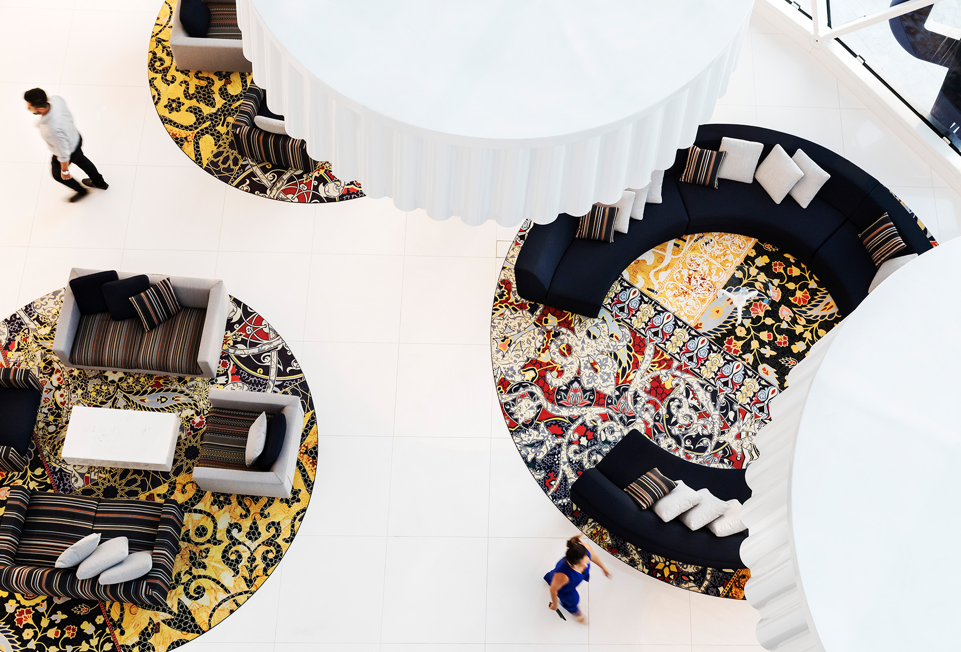 Una vista aérea del vestíbulo de un hotel con islas redondas y coloridas para sentarse.