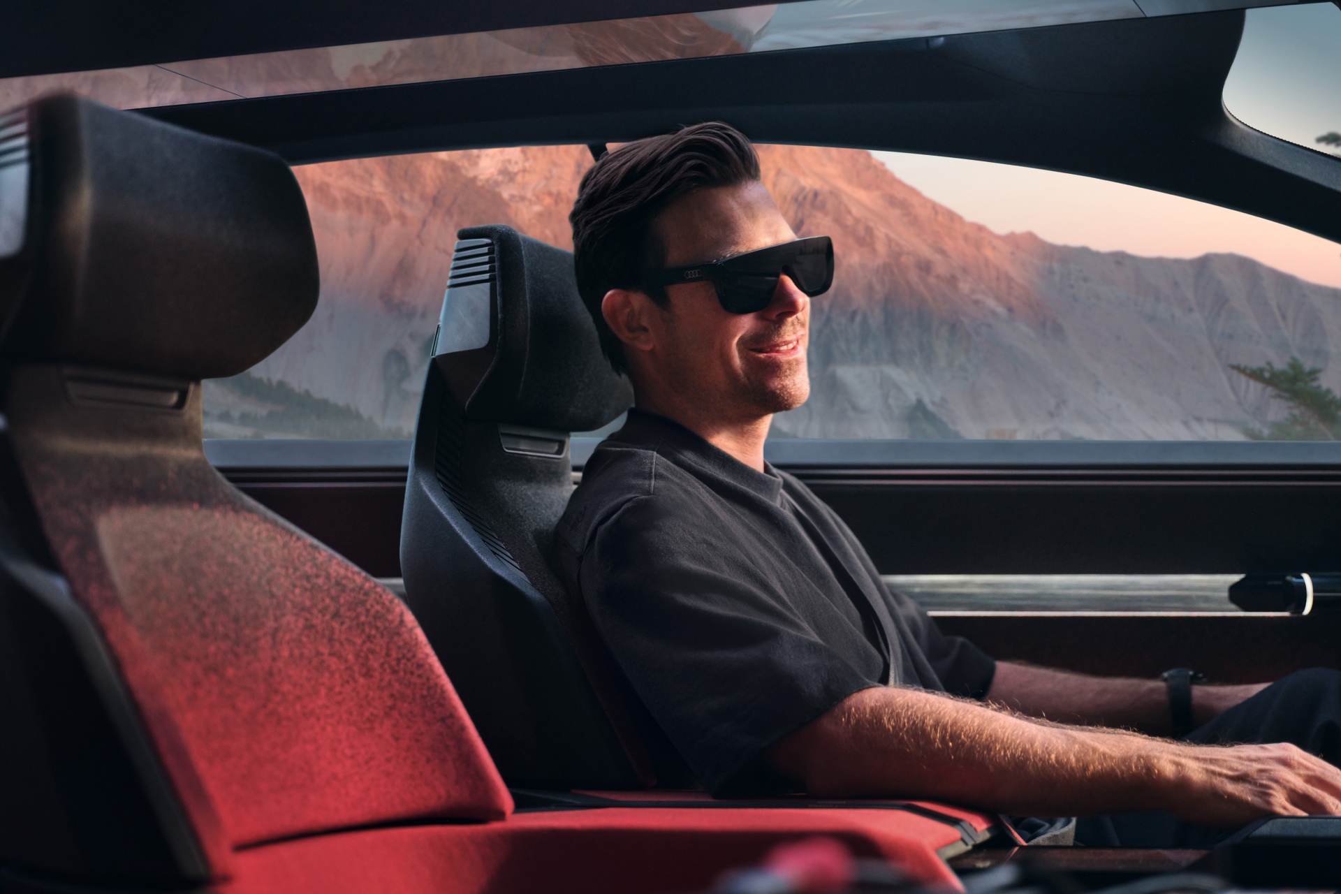 Hayden Cox está sentado en el Audi activesphere concept con gafas AR.