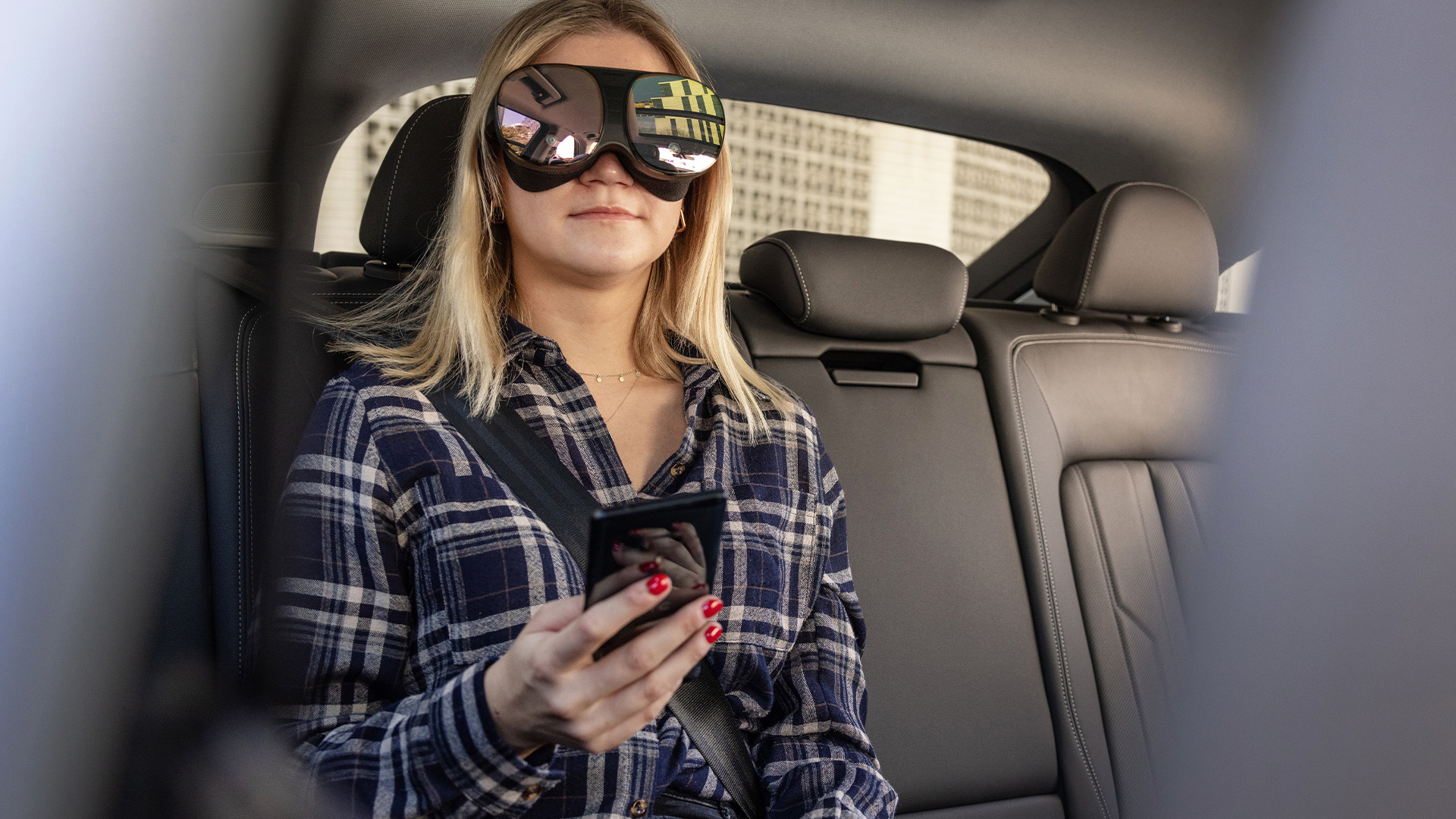 Una mujer sentada en el asiento trasero de un vehículo que utiliza tecnología holoride a través de un visor de realidad virtual.